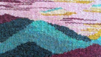 close up of a wool tapestry weaving showing mountains and sky