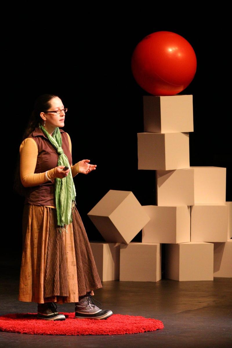 Jacqueline standing on a red carpet circle on stage at TEDx Couer d'Alene