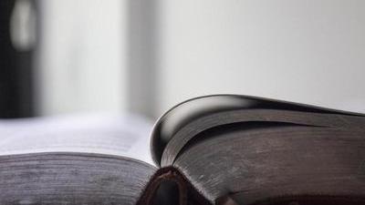 open thick book, viewed from the spine laid flat on a table