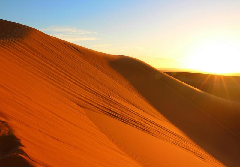 sun setting on a hill of red sand in the Sahara Desert