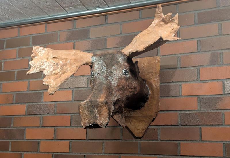 paper mache moose head hanging on a brick wall