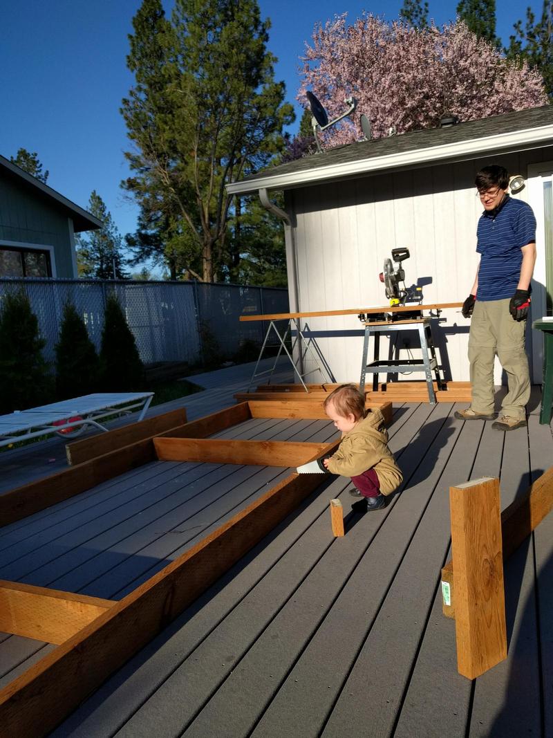 our 2-year-old using a plastic saw to try to cut wood on our back deck