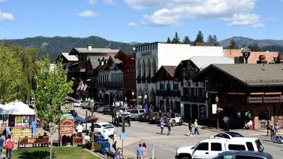 Leavenworth, Washington, a Bavarian themed downtown Main Street with people walking along the street in the sunshine and cars parked along the edges of the road