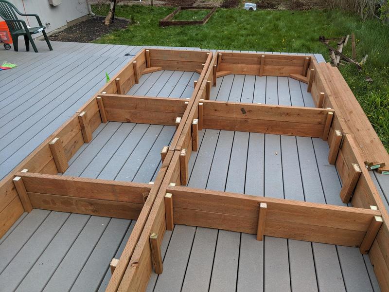 2x6 pieces of wood stacked and arranged on the deck into the shape of a rectangular garden bed, ready to be screwed together