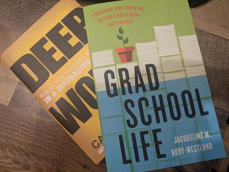 the books Deep Work by Cal Newport and Grad School Life by Jacqueline Kory-Westlund stacked up on a table