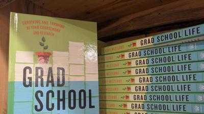 copies of the book Grad School Life on a bookshelf