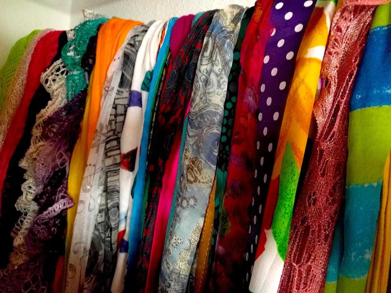 A row of colorful scarves hanging in a closet