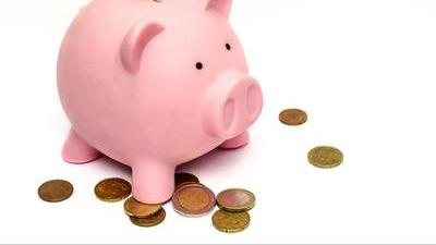 pink piggy bank standing on top of a pile of coins