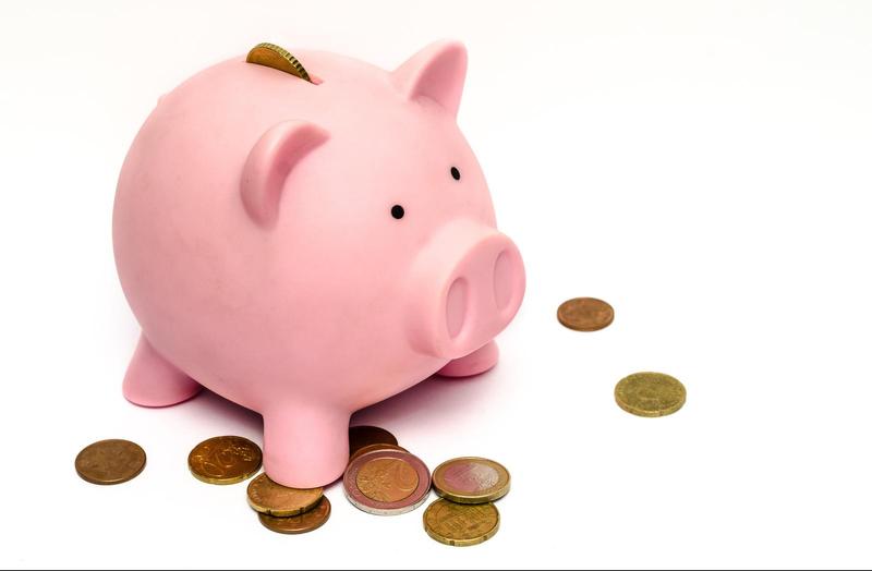 pink piggy bank standing on top of a pile of coins