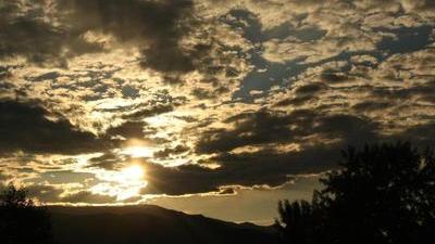 sun setting behind clouds hills silhouetted