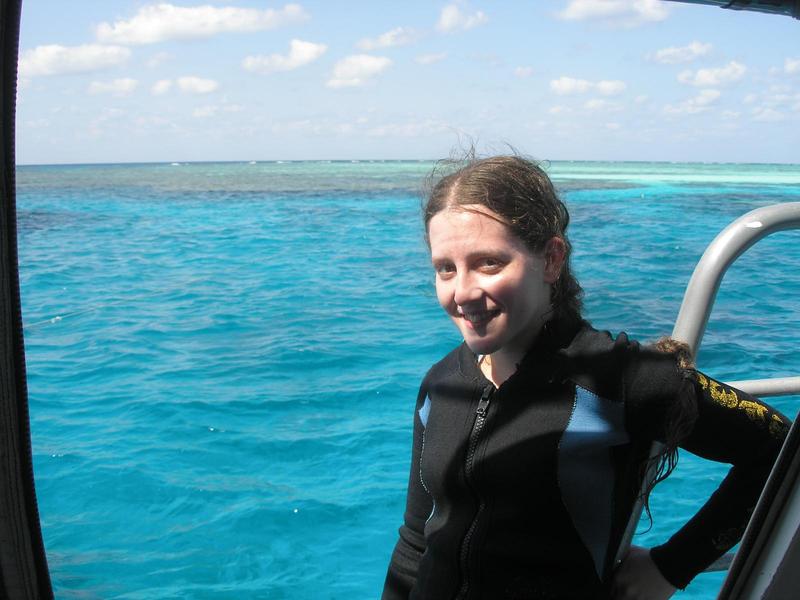 jacqueline in a wetsuit on a boat smiling, blue Australian water behind her