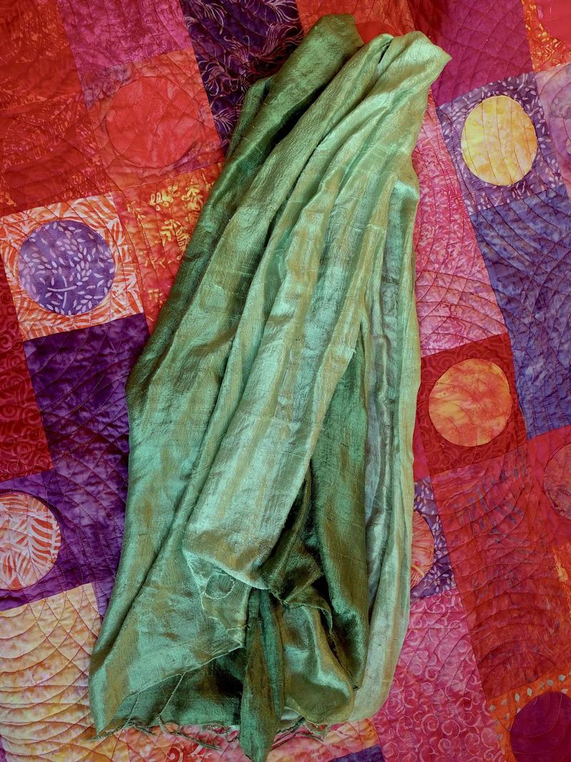 a linen green scarf lying on a bed