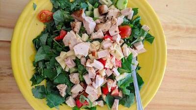 ceramic plate with a fresh salad: spinach, lettuce, cucumbers, tomatoes, chicken, cheese