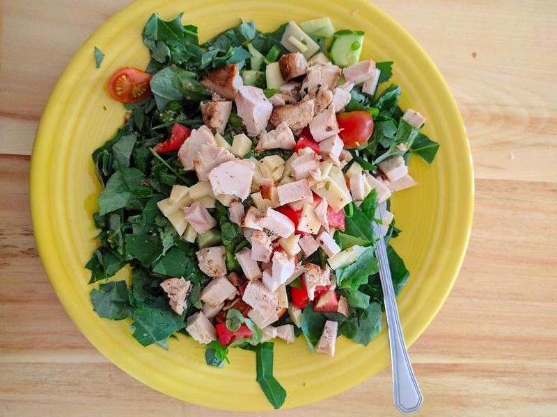 ceramic plate with a fresh salad: spinach, lettuce, cucumbers, tomatoes, chicken, cheese