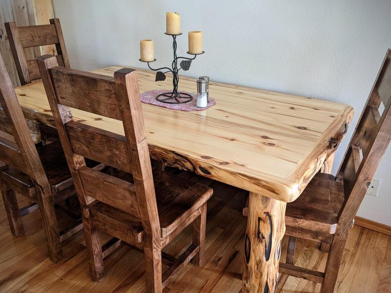 a big rectangular aspen pine wood table with dark wood chairs beside it