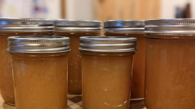 Mason jars of apple jam lined up on a wooden cutting board
