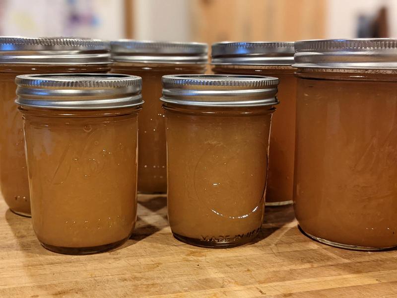 Mason jars of apple jam lined up on a wooden cutting board