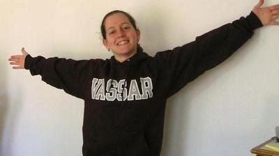 Jacqueline in a Vassar sweatshirt, grinning with arms outstretched