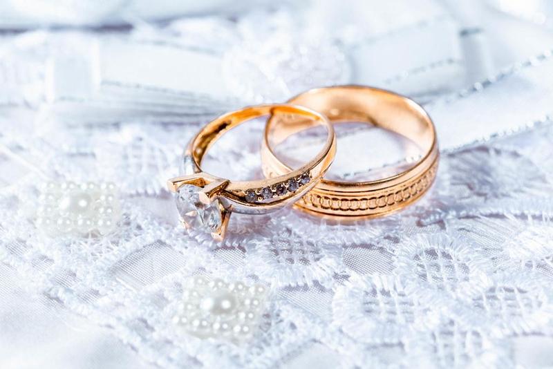 closeup of gold wedding rings on a lace table