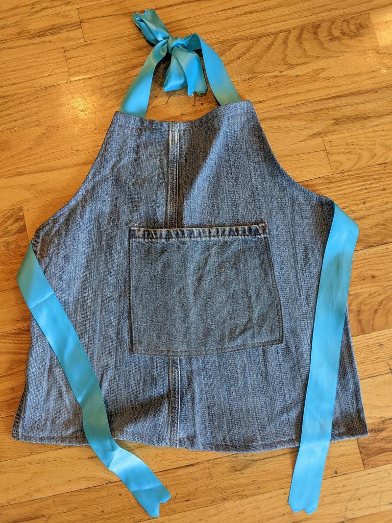 kids size apron made from old blue jeans laying flat on the floor