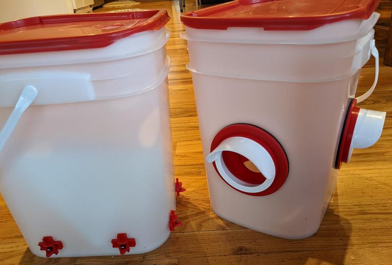 two five gallon buckets, one with horizontal nipples for chickens to drink from and the other with two pvc elbows for chickens to eat from