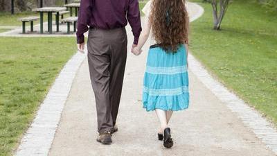 randy and jacqueline walking away on a path in a park toward trees and grass