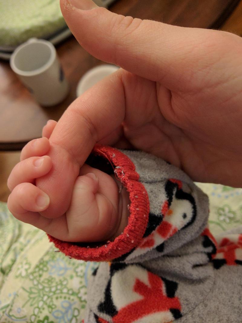 Our first son's tiny hand gripping Jacqueline's finger