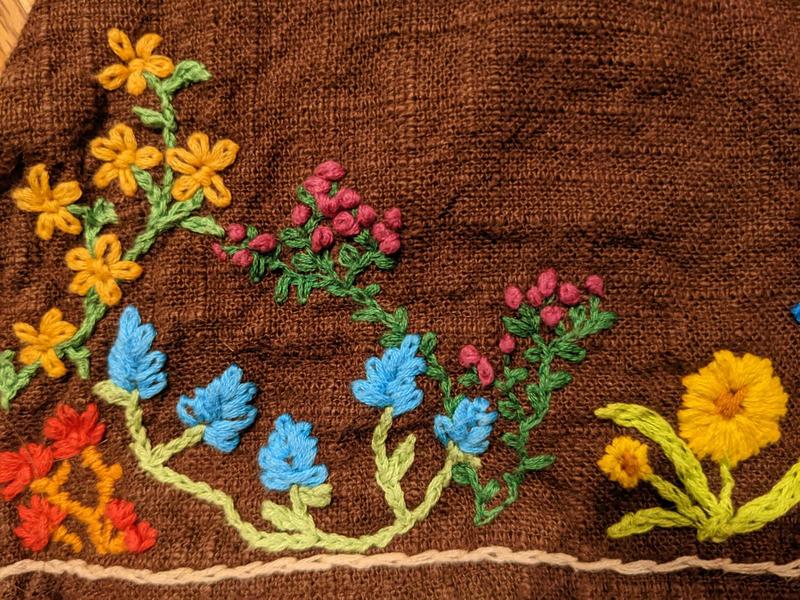 close up of embroidered flowers on the edge of a linen skirt