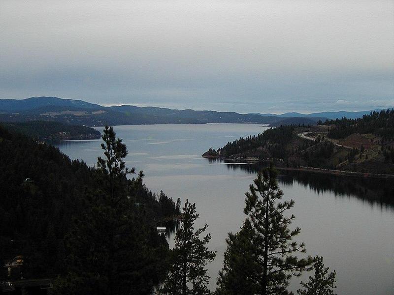 Lake Coeur d'Alene on a cloudy day, glassy surface, dark hills and trees and a misty sky