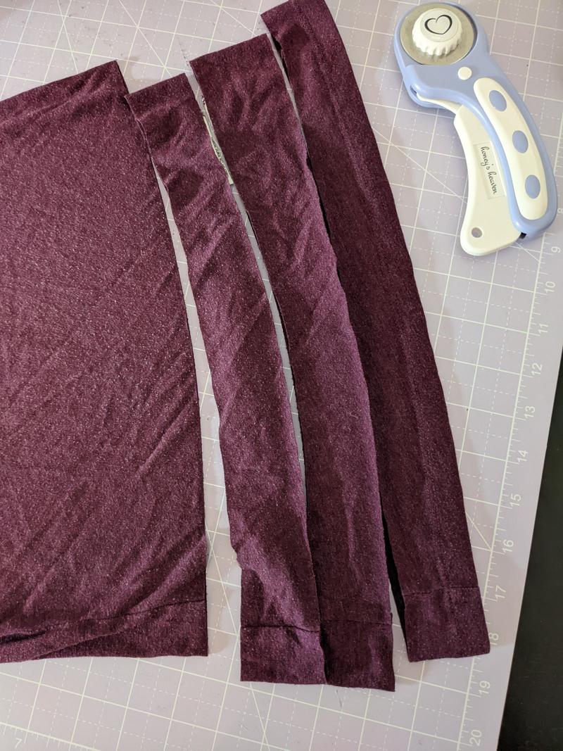 a tshirt laying on a cutting mat with three strips cut off the bottom edge, each about two inches wide