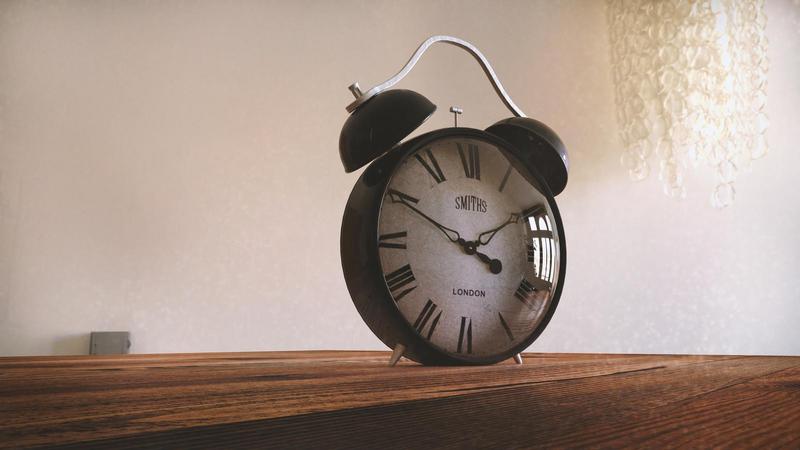 old fashioned alarm clock sitting on a wood table