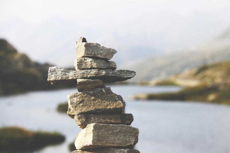 a rock cairn of angular stones with a river blurred in the background