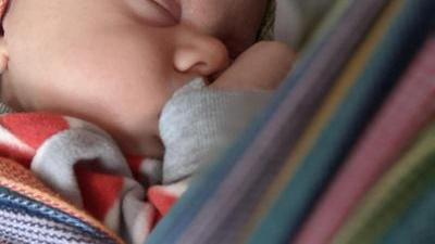 baby sleeping in a woven wrap on his mother