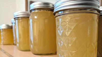 pint size mason jars filled with honey in a line on a wooden surface