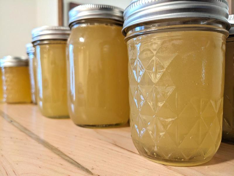 pint size mason jars filled with honey in a line on a wooden surface